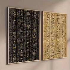 two framed art pieces on the wall with egyptian writing in gold, black and white