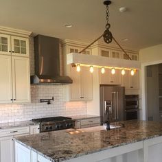 a large kitchen with white cabinets and granite counter tops, an island in the middle