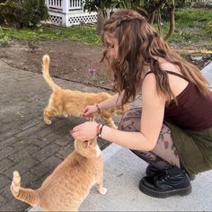 a woman petting an orange and white cat on the sidewalk in front of a house