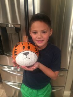 a young boy holding a pumpkin shaped like a tiger