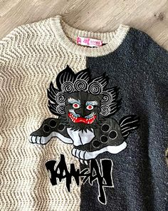 a black and white sweater with an image of a demon painted on it's chest