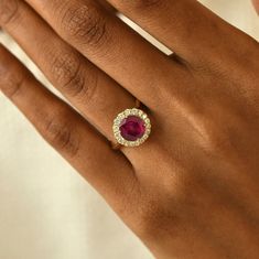 a woman's hand holding a ring with a ruby and white diamond in it