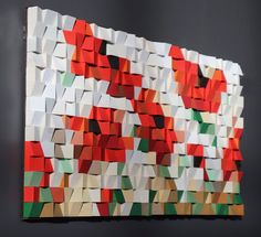 an abstract piece of art made out of different colored blocks and shapes on a black wall