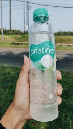 a person holding up a bottle of water in their hand with the label pristinee on it