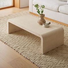 a living room with a couch, coffee table and rugs on the floor in front of it