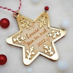 a personalized christmas ornament hanging from a red and white string with ornaments around it