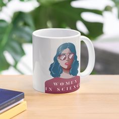 a coffee mug with the words women in science on it sitting next to some books