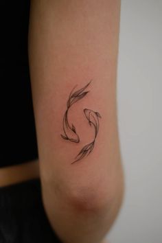 a woman's arm with a small black fish tattoo on the left side of her body