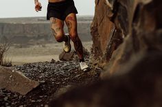 a man running up the side of a rock wall in front of a cliff face