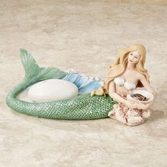 a mermaid figurine sitting on top of a table next to a white ball