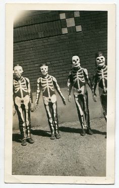 an old black and white photo of three skeletons walking down the street with their hands in each other's pockets