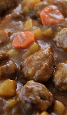 meatballs and carrots are in a white bowl on a wooden table next to bread