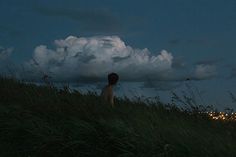 a boy sitting on top of a grass covered hill under a cloudy sky with the words in spanish above him