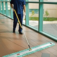 a man with a mop is cleaning the floor in front of a large window