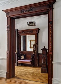 an ornately carved wooden mirror in the corner of a room with wood flooring