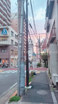 an empty city street with power lines above it and buildings on both sides, in the background