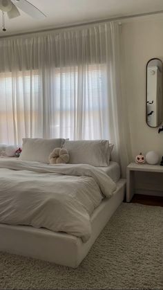 a large bed sitting under a window next to a white dresser and mirror in a bedroom