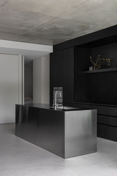 an empty kitchen with black cabinets and stainless steel counter tops