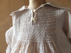 a white dress with buttons on the collar