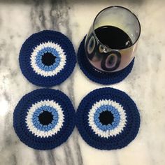 three crocheted coasters with blue and white circles on them next to a cup