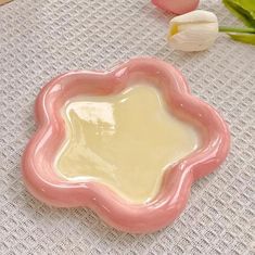 a pink flower shaped dish sitting on top of a table next to tulips