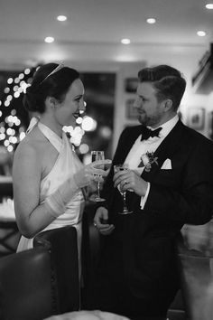 a man and woman standing next to each other holding wine glasses