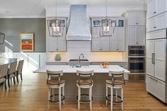 a kitchen with white cabinets and an island in the middle, surrounded by wooden flooring