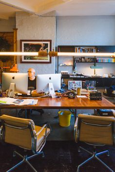 an office with two people working on their computers and one person sitting at the desk