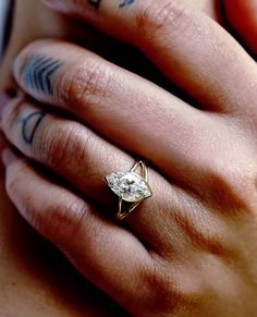 a woman's hand holding a ring with a diamond in the middle and tattoos on it