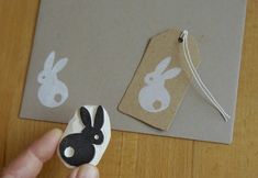 a hand holding a rubber stamp next to a piece of paper with bunny ears on it