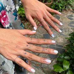 two women's hands with tattoos on their fingers and one holding her hand out