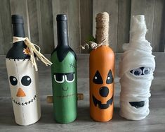 three wine bottles decorated as halloween characters and one with a bandage wrapped around the bottle