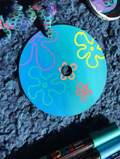 a blue painted disc with flowers on it and some crayons next to it