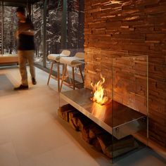 a fire place in the middle of a room with wood and glass on the wall