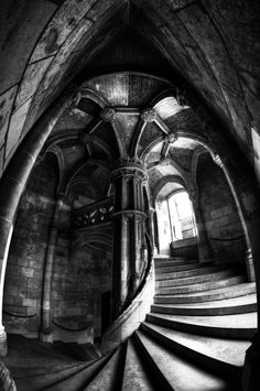 a spiral staircase in the middle of a building with stone walls and arched doorways