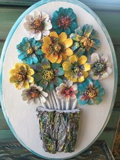 a vase with flowers in it sitting on top of a wooden wall hanging from a blue frame