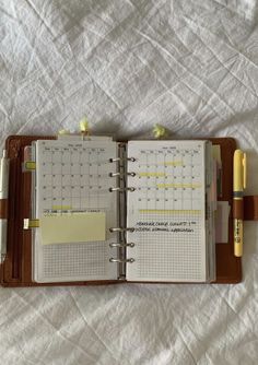 an open planner and pen sitting on top of a bed