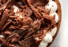 a chocolate pie with whipped cream and chocolate shavings on top is ready to be eaten