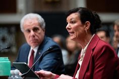 two people sitting at a table with microphones in front of them and one person holding a laptop