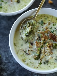 two white bowls filled with broccoli and cheese soup