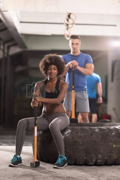 a woman sitting on top of a tire with a pole in her hand and a man standing next to her