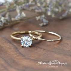 two gold wedding rings with a single diamond on top of each other and lavender flowers in the background