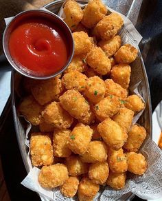 a basket filled with tater tots next to ketchup and dipping sauce