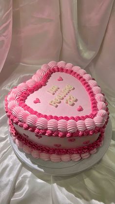 a heart shaped cake with pink frosting on top