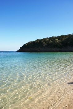 the water is crystal blue and clear with little waves coming in from the sand on the beach