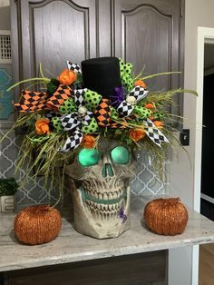 a skull with green eyes and a top hat sitting on a counter next to two pumpkins