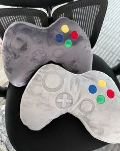 two game controllers are sitting next to each other on a chair cushion in front of a computer desk