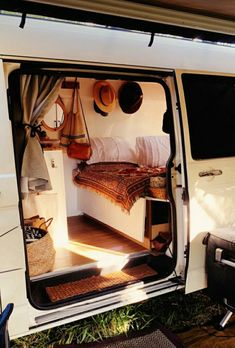 the interior of a camper van with its door open and bed in it's back