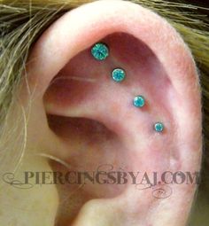 a woman's ear with three different colored stones on it