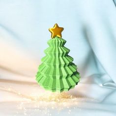 an origami christmas tree with a gold star on top and snow flakes around it